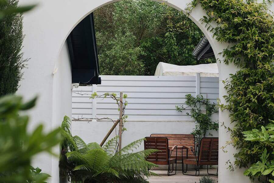 Garden privacy ideas | beautiful photo of open stone garden gate with seating area behind it.